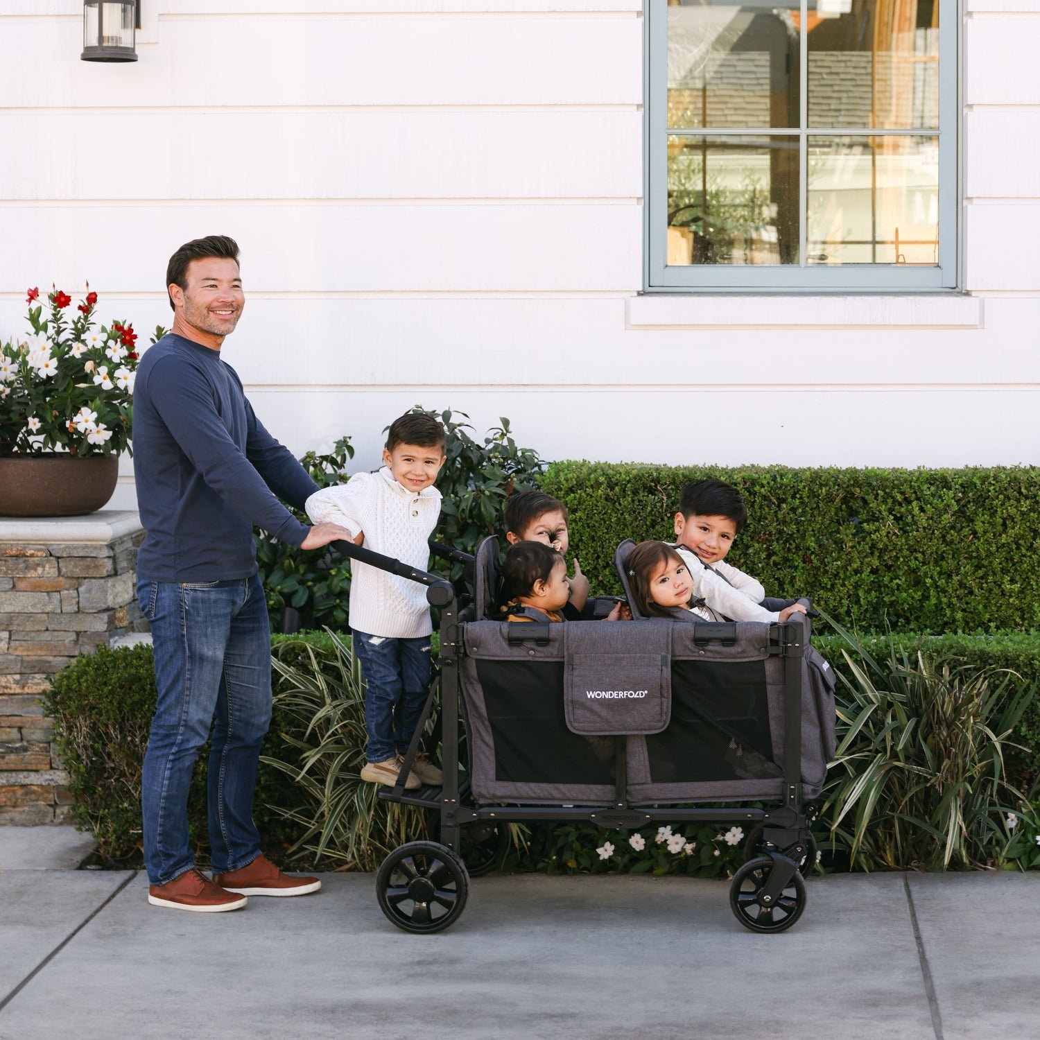 Family using the WonderFold stroller wagon with the Buddy Board accessory for a comfortable outing
