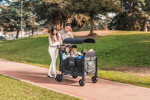 Family strolling through a park with their WonderFold 4 seater wagon, perfect for outings