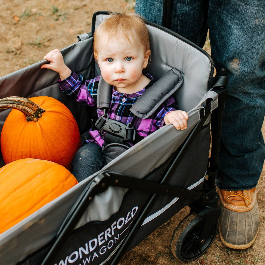 Baby sitting in WonderFold wagon filled with pumpkins