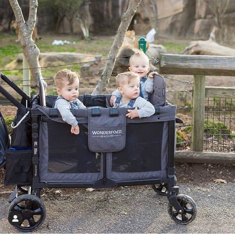 Three toddlers enjoying a ride in a WonderFold wagon during a visit to the zoo